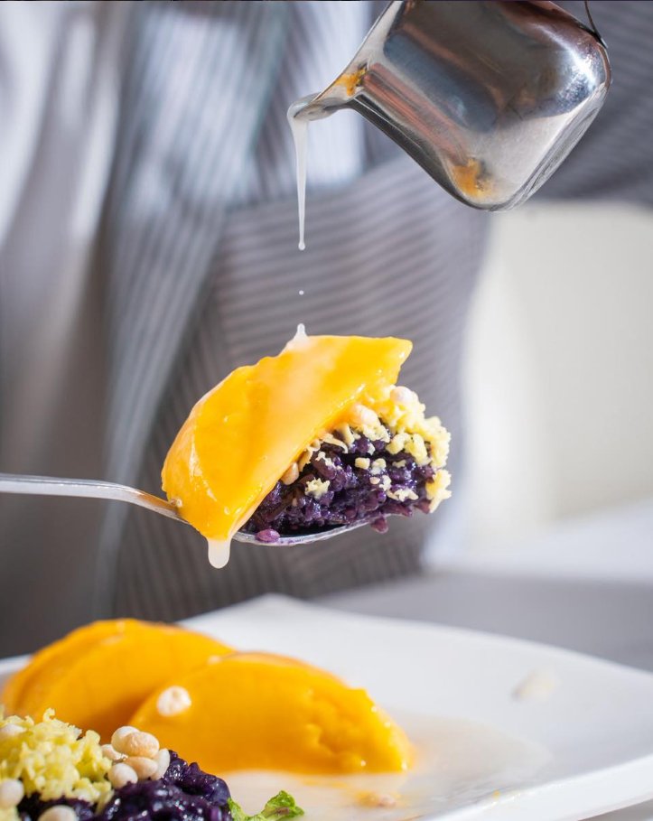 Ube mango sticky rice with coconut sauce being poured on top