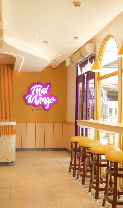 Inside Thai Mango, with the glowing logo sign and yellow bar stools